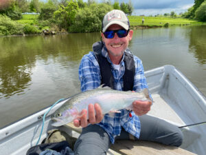 Successful flyfisher holding a rainbow trout