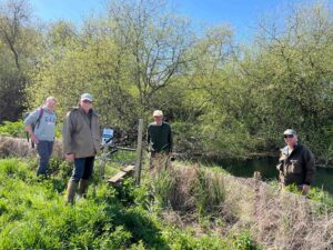 Working party members on an early spring day prepping for the flyfishing season on a blue sky day with trees