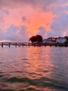 Morning sunrise in Poole harbour with red sky reflecting on water and tree ane bank